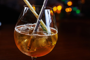Bright strong alcoholic cocktail with a creative decoration of chocolate sticks and ice cubes on a table in a restaurant with backgrounds of colored disco lights. soft focus and beautiful bokeh.