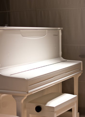 White piano in the dark. Piano chair
