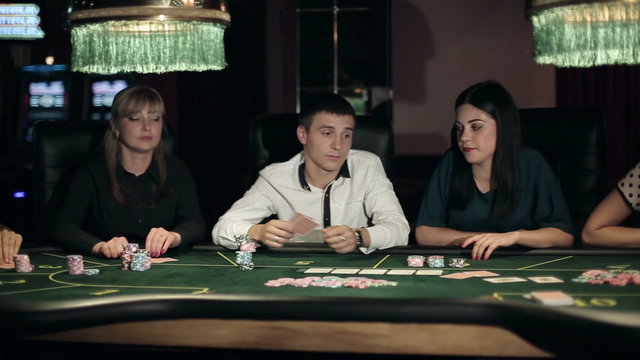 Casino, poker: Group of people in poker club gambling at poker card table. Slider camera movement