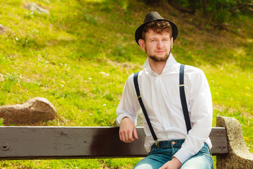 young man retro style sitting on bench in park