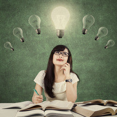 Smart learner sitting under light bulb