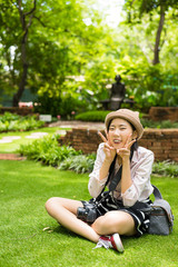 Cute young Asian girl is sitting with her dslr camera in wilderness garden natural summer atmosphere 