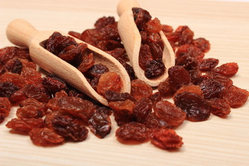 Brown raisins with spoon on wooden table, healthy eating