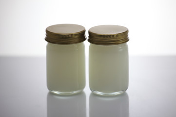 Pain relief balm in glass, white background.