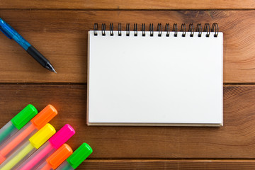 Notebook with a pen on a white wooden floor highlights.