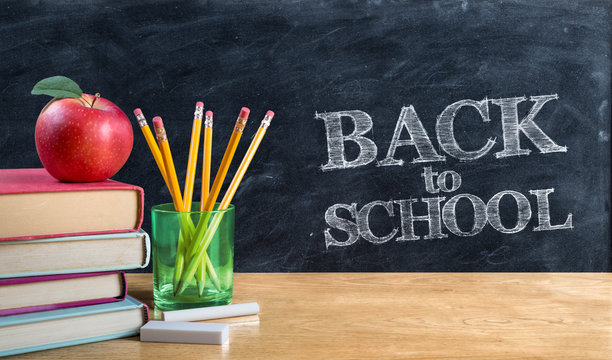 back to school - apple on books with pencils and blackboard

