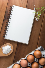 Notebook white on a wooden floor with egg dishes.