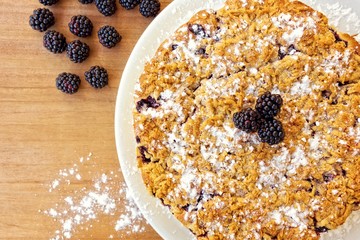 Fresh baked cake, with blackberries fruit on top of it. Set on wooden table.