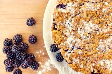 Fresh baked cake, with blackberries fruit on top of it. Set on wooden table.