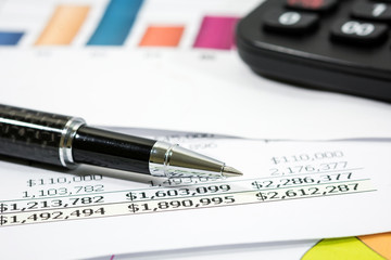 Black pen with financial report and calculator  
