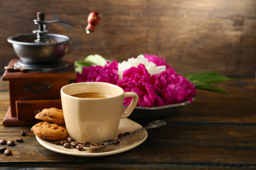 Composition with, coffee grinder, cup of coffee and peony flowers on wooden background