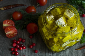 feta cheese in olive oil and herbs on a wooden table surrounded