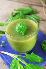 Glass of green healthy juice with spinach and peas on table close up