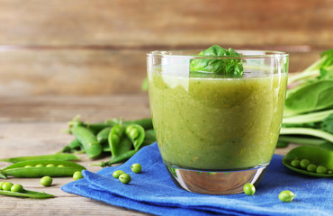 Glass of green healthy juice with spinach and peas on table close up