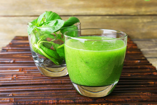 Glass of green healthy juice with spinach and basil on table close up