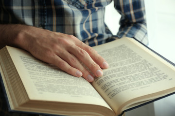 Young man reading book close up