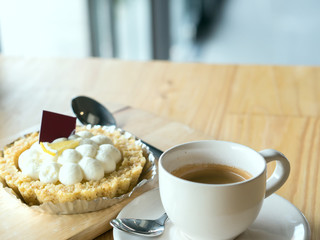 Warm tone of a cup of espresso coffee and blurry cake on wooden