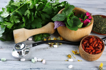 Alternative medicine herbs and stethoscope on wooden table background