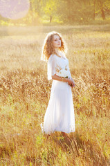 Fototapeta na wymiar Woman with curly golden hair smiling standing in the field