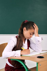Beautiful little schoolgirl in classroom near blackboard
