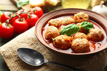 Meat balls with tomato sauce, wooden spoon on wooden background