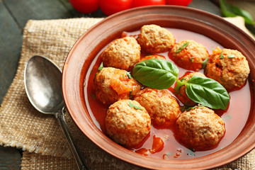 Meat balls with tomato sauce, wooden spoon on wooden background