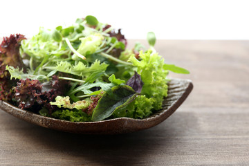Plate of fresh mixed green salad on wooden table close up