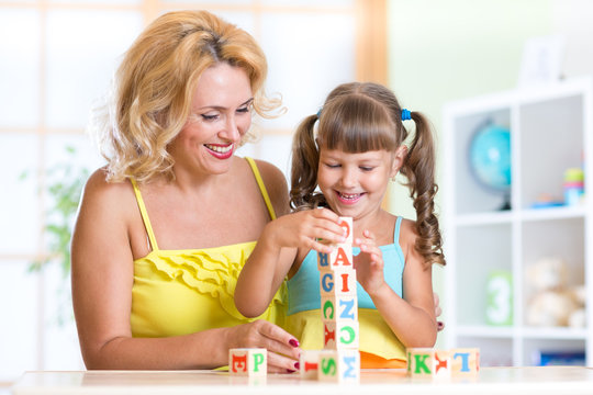 child and mom playing wooden toys at home