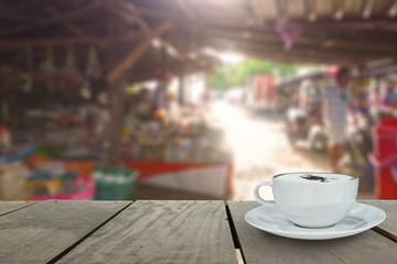 Coffee cup on terrace wood and Local market blur background