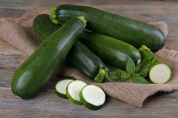 Fresh zucchini with basil on wooden table close up