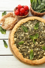 Open pie with spinach and tomato cherry on table close up