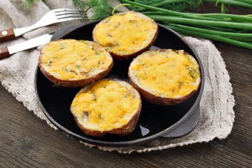 Baked potato with cheese in pan on wooden table, closeup