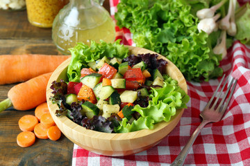 Wooden bowl of fresh vegetable salad on table, closeup