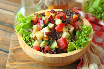 Wooden bowl of fresh vegetable salad on table, closeup