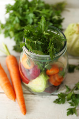 Fresh vegetables in glass bottle on wooden table, closeup