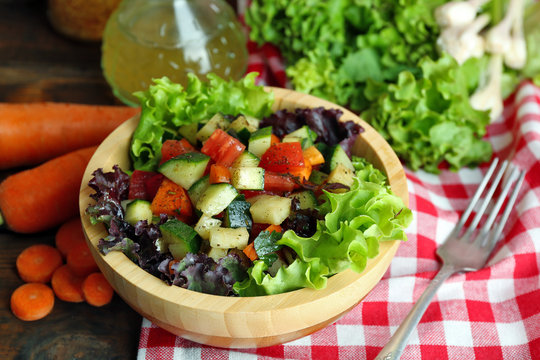 Wooden bowl of fresh vegetable salad on table, closeup