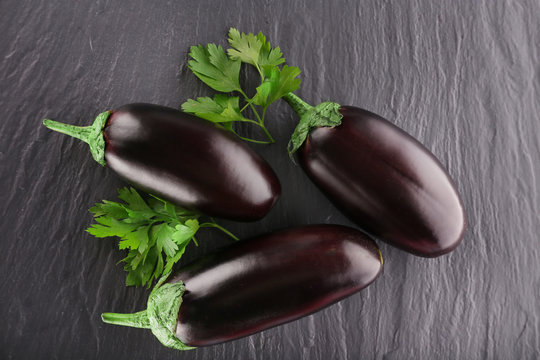 Fresh eggplant with parsley on wooden background