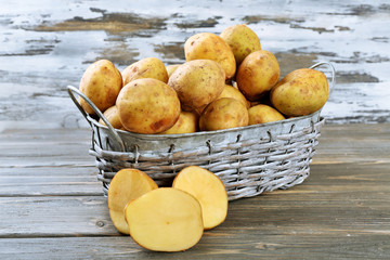 Young potatoes in wicker basket on wooden background