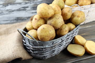 Young potatoes in wicker baskets on wooden table close up