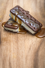 Image with a rustic feeling of two Ice Cream sandwiches on a wooden table covered in caramel