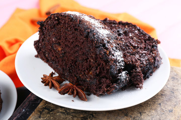 Delicious chocolate roll in saucer on book, closeup