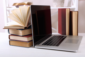 Stack of books with laptop on table close up