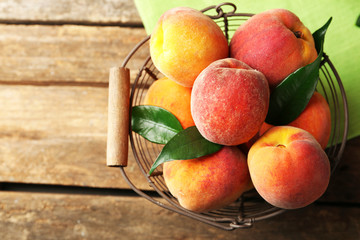Ripe peaches in basket on wooden background