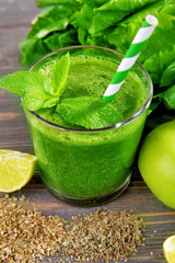 Green healthy juice with fruits and herbs on table close up