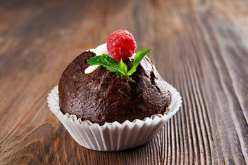Delicious chocolate cupcake with raspberry on wooden table close up