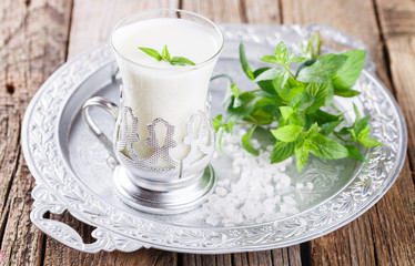 A glass of buttermilk and a bunch of mint on the tray.Milk product. selective focus