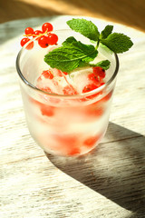 Glass of cold refreshing summer drink with berries and ice cubes on table close up