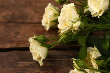Beautiful small roses on wooden table close up