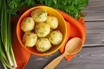 Boiled potatoes with greens in bowl on table close up