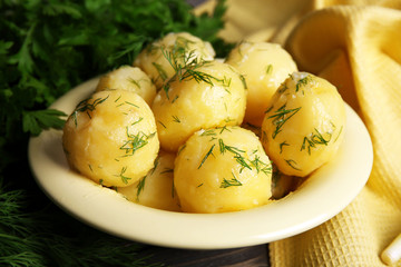 Boiled potatoes with greens in bowl on table close up